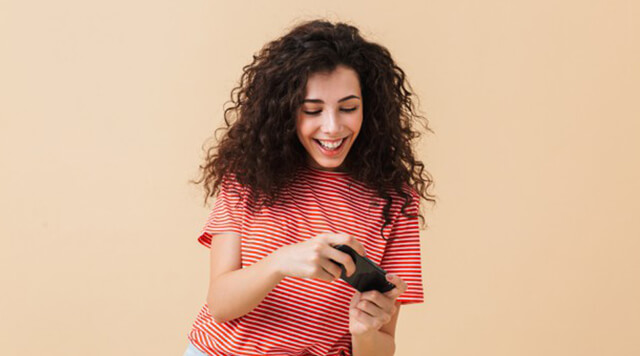 A photograph of a woman playing and enjoying games on her mobile phone. - Chaos Theory | Serious Games Developer, Australia